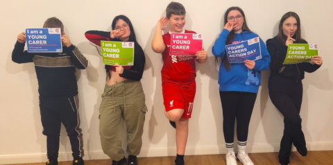 Five young carers lined up against a wall with Young Carers Action Day posters
