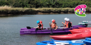 Three young carers in a canoe on river with 'We are Young Carers' logo to top right