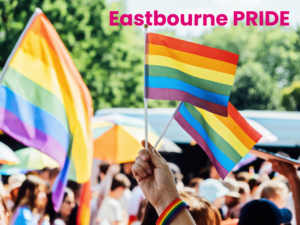 Photo of pride flags being waved in the air, with lots of people in the background