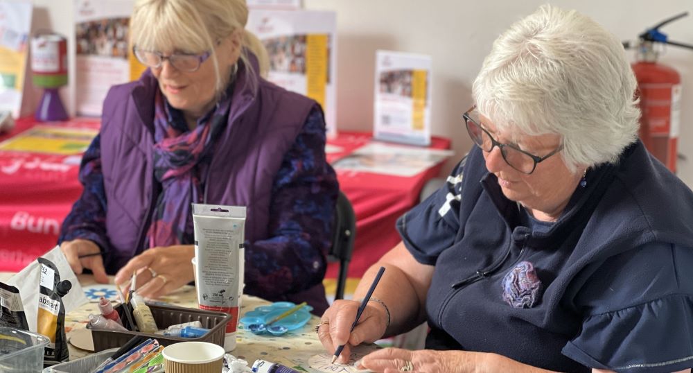 Two carers doing a craft activity at a table.